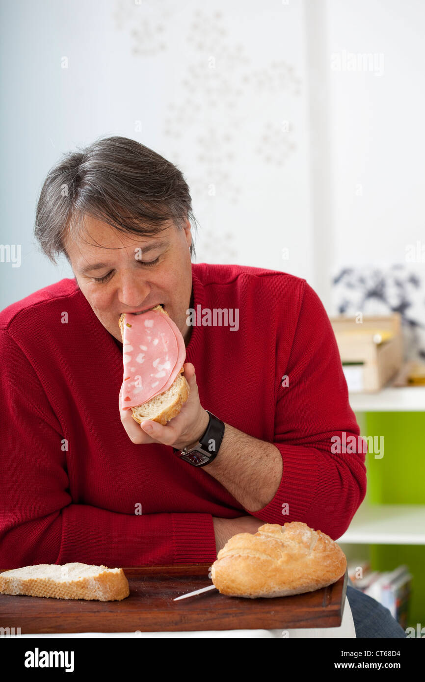 MAN EATING PORK MEAT Stock Photo