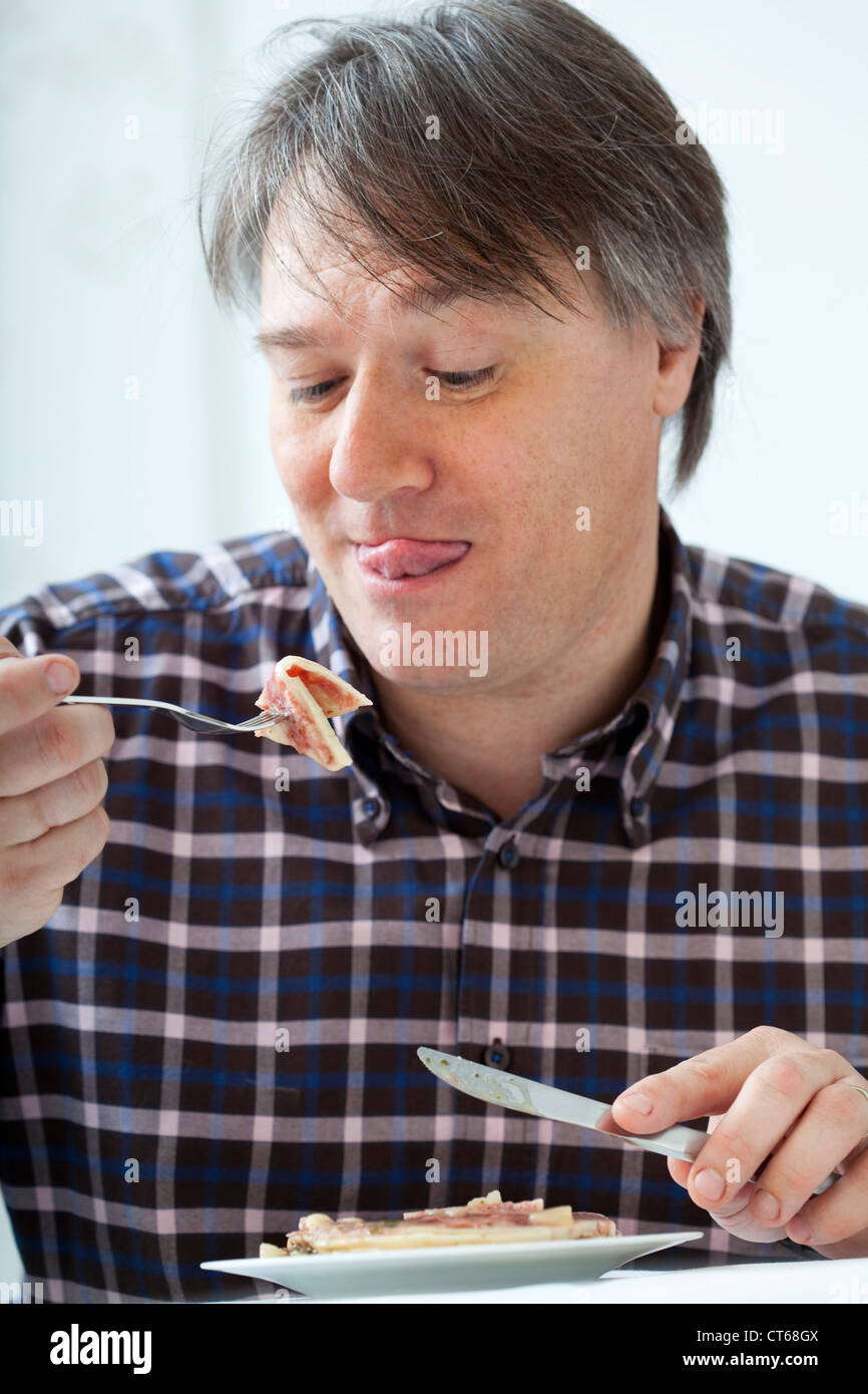 MAN EATING PORK MEAT Stock Photo Alamy
