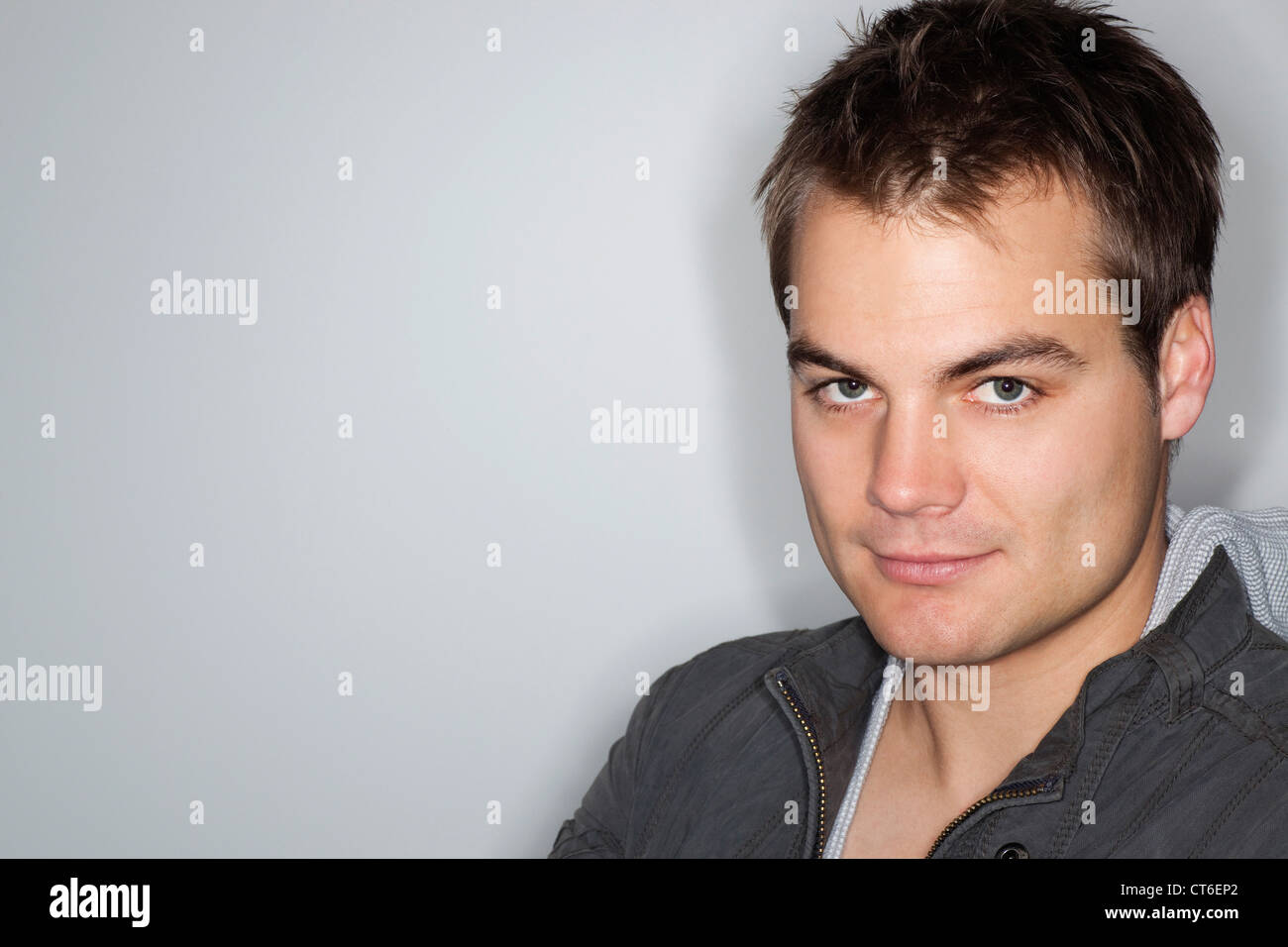 Portrait of a handsome young man smiling against gray background Stock ...