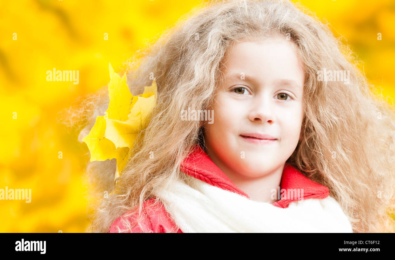 Beautiful and happy little girl with maple leaf in her hair. Smiling ...