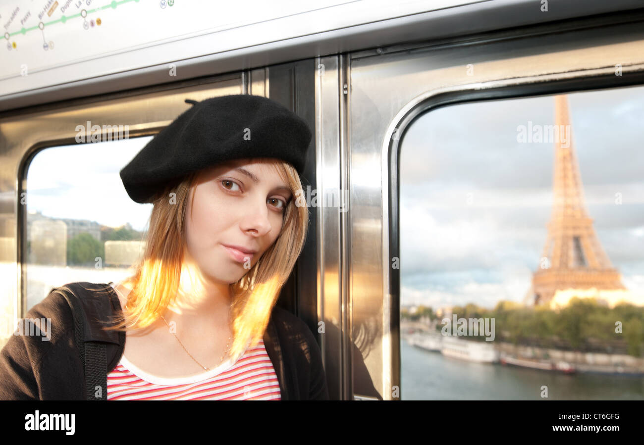 Beautiful and happy young woman in Paris metro. Eiffel tower seen through the train window. Paris, France, Europe. Stock Photo