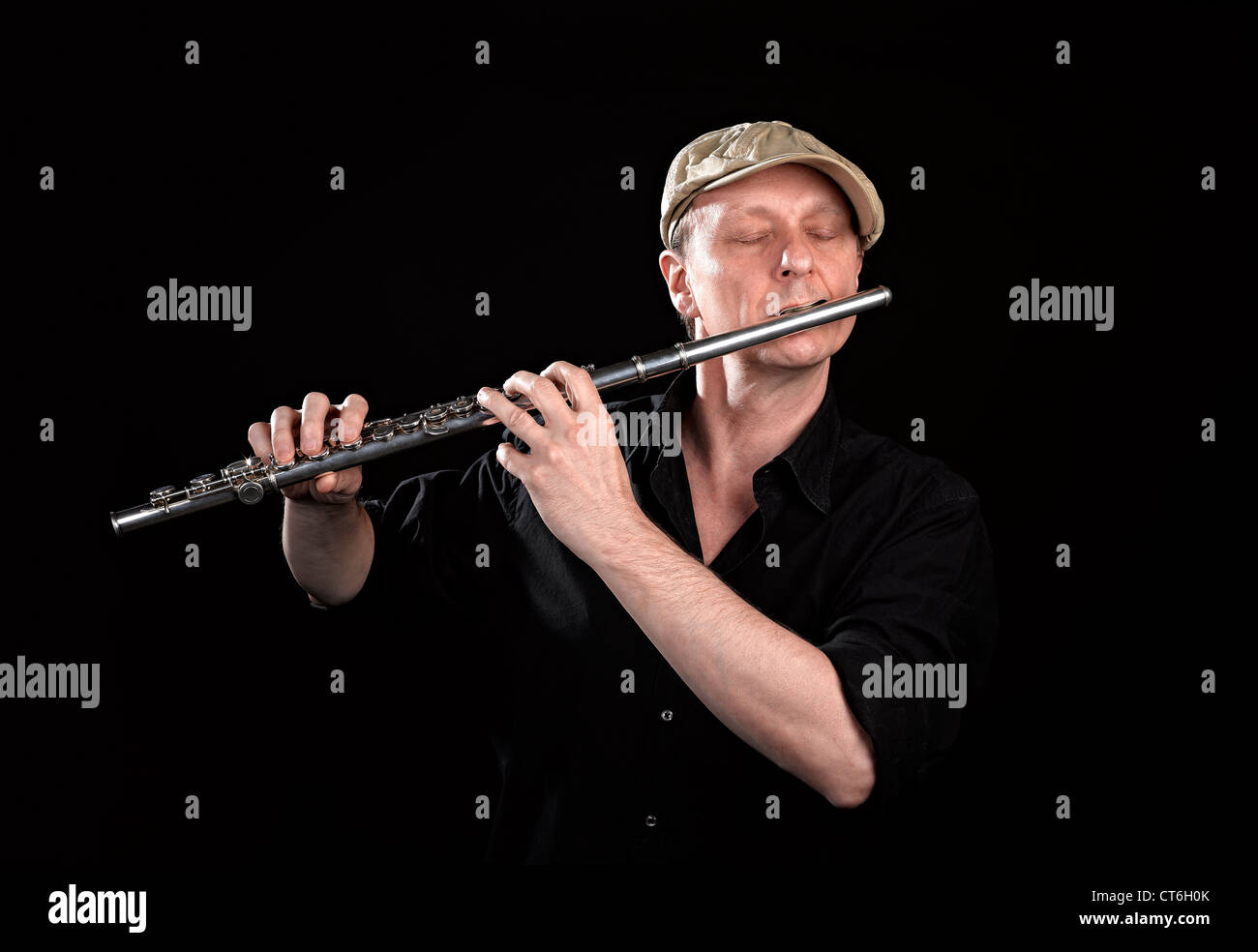 Portrait of a man playing old silver transverse flute on black background Stock Photo