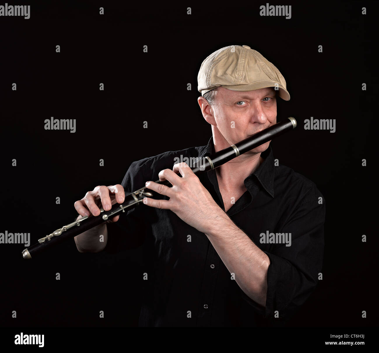 Portrait of a man playing ols wooden transverse flute, isolated on black Stock Photo