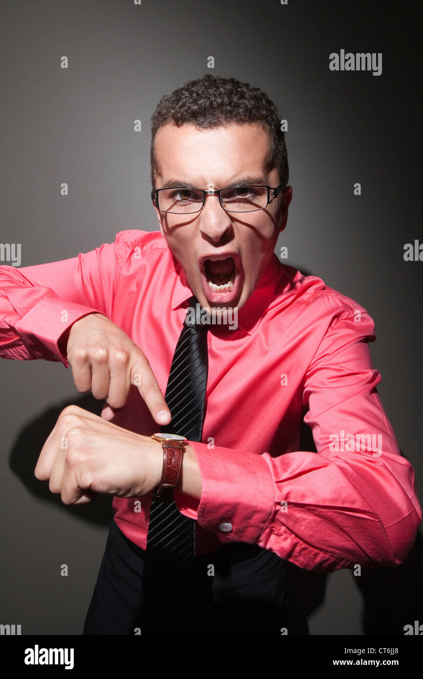 Aggressive businessman pointing at time on watch Stock Photo