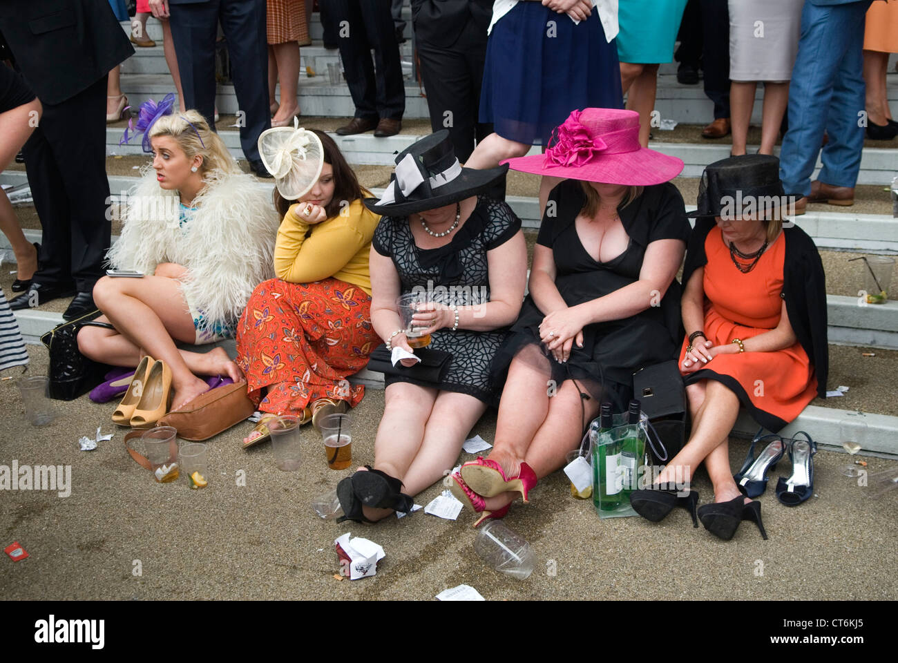 Tired exhausted, sore feet, worn out, uncomfortable shoes, group of women sitting down  and looking at their feet. 2012 2010s UK HOMER SYKES Stock Photo