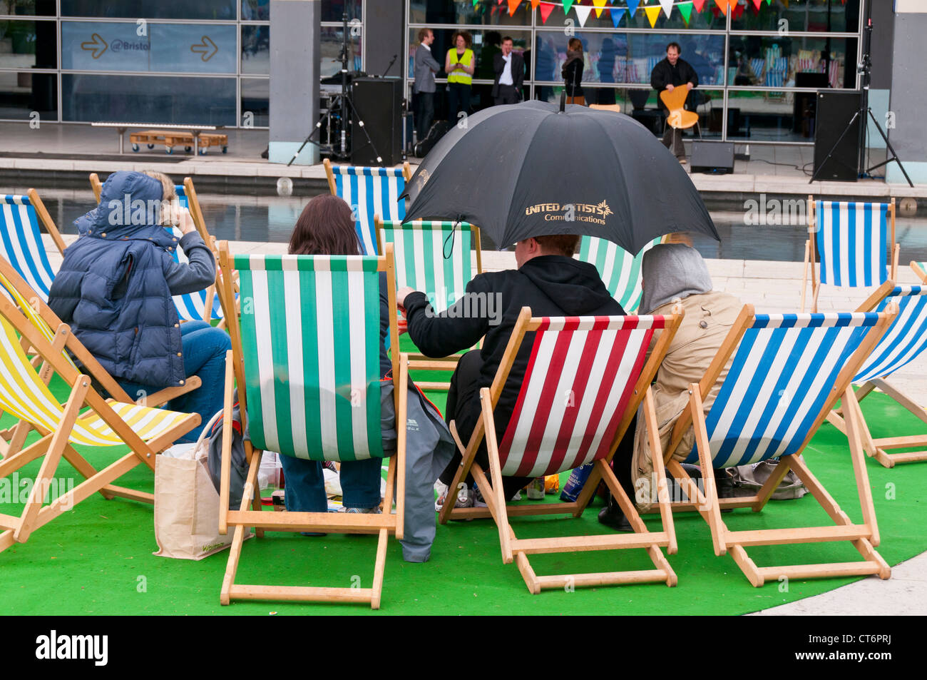 People enjoying themselves despite bad weather in Millennium Square in the City Centre of Bristol, UK Stock Photo