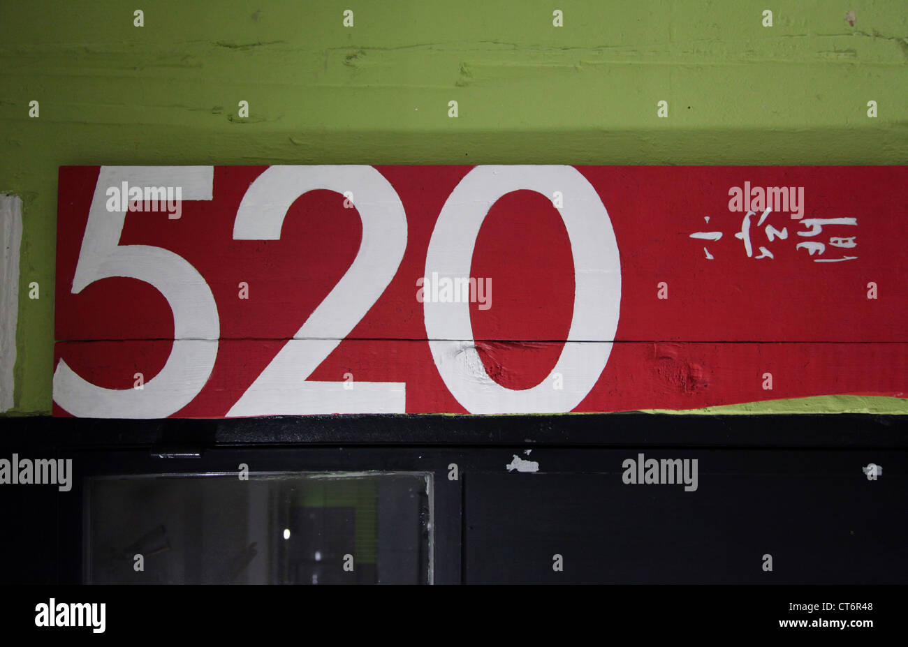 It's a photo of a number painted on a wall in a parking underground a building. We can see 520 or 6 or 8 in colors Stock Photo
