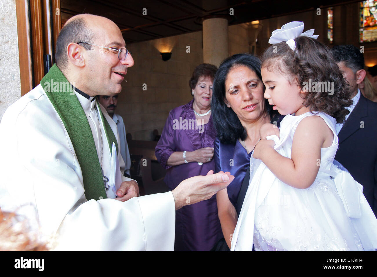 Lutheran Minister Dr. Mitri Raheb with baptised girl and her aunt in the lutheran Christmas church in Bethlehem, Palestine Stock Photo