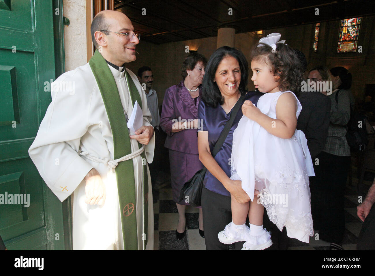 Lutheran Minister Dr. Mitri Raheb with baptised girl and her aunt in the lutheran Christmas church in Bethlehem, Palestine Stock Photo