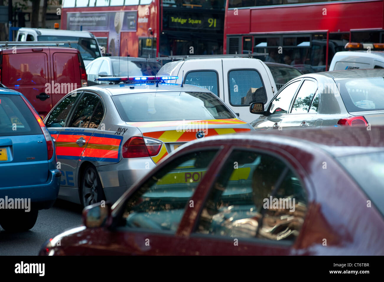 A police car with blue flashing lights tries to make its way through heavy traffic in the centre of London, England. Stock Photo