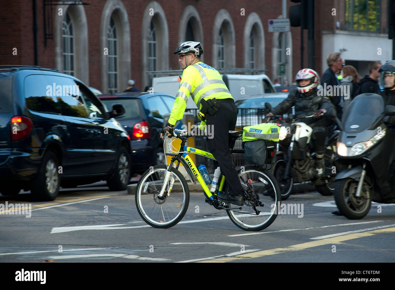 Policeman riding a bicycle through busy traffic in the city of London