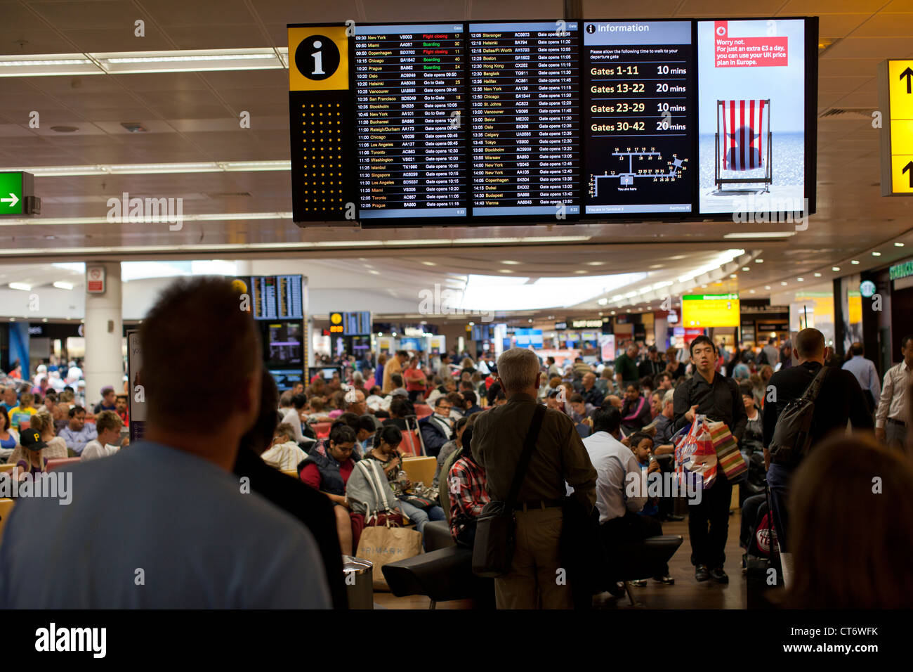 Airline passengers look for their flight departures on an electronic board at London, England's Heathrow Airport in Terminal 3. Stock Photo
