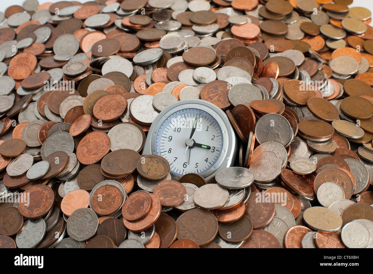 A clock in a pile of money Stock Photo