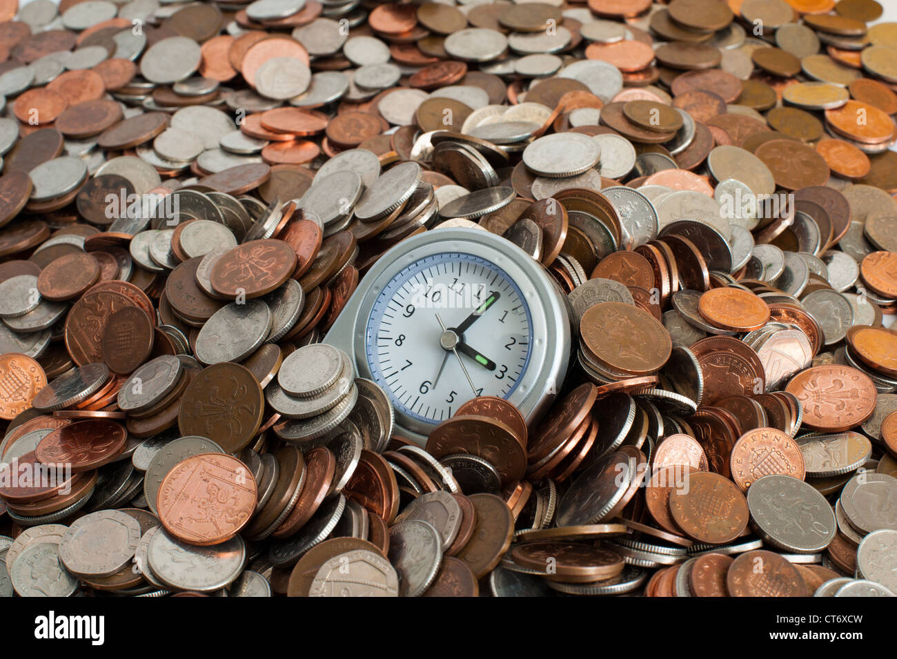 Clock in a pile of money Stock Photo