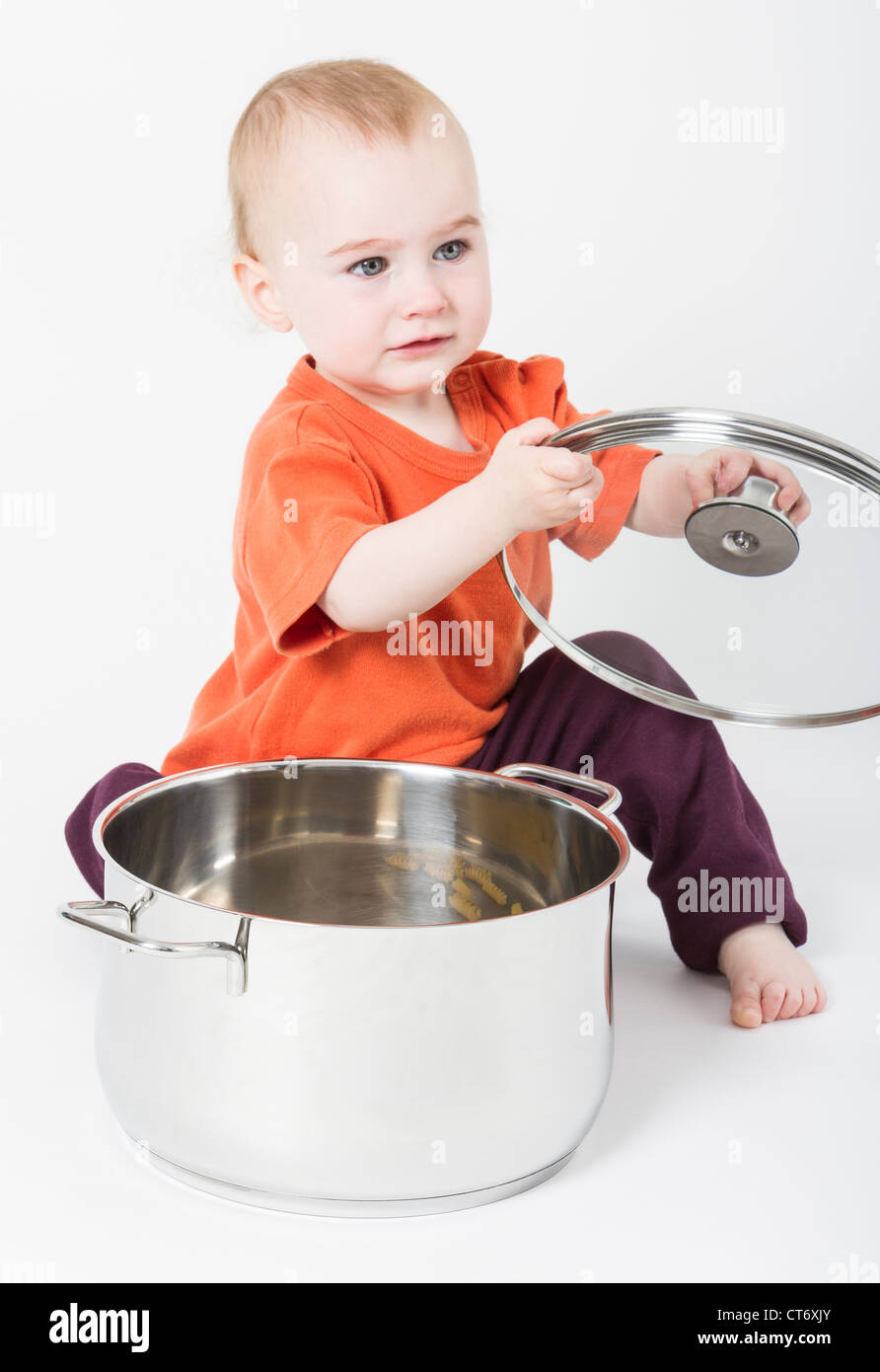 baby with big cooking pot on neutral background Stock Photo