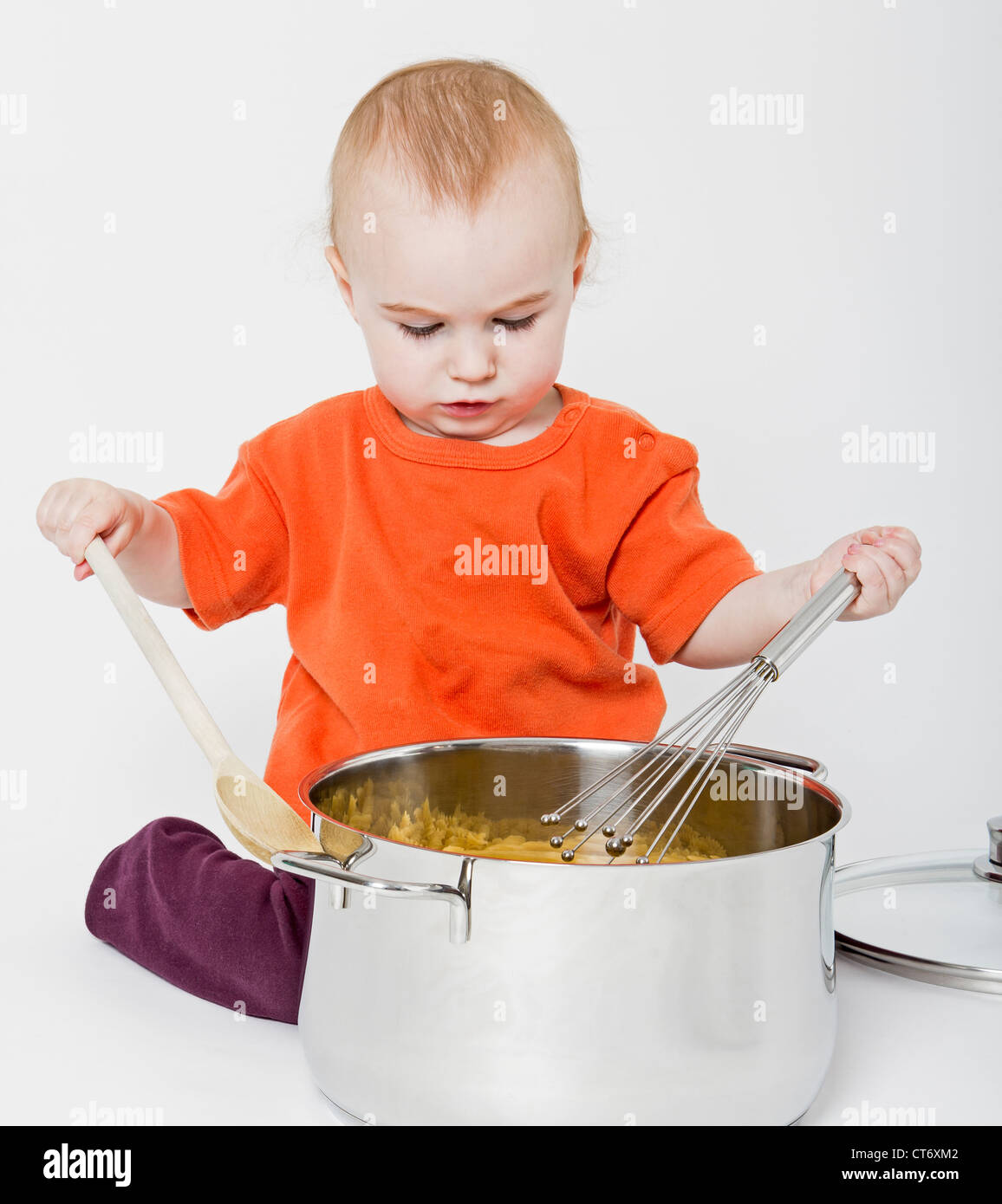 baby with big cooking pot on neutral grey background Stock Photo