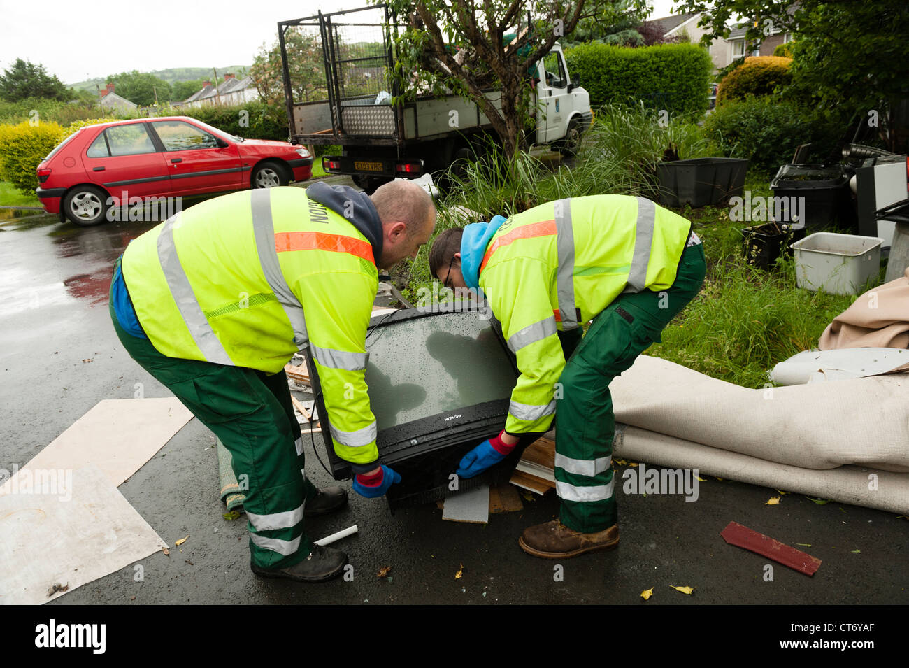Council workers load a television on to a truck for disposal after the flash floods that damaged houses in Aberystwyth June 2012 Stock Photo