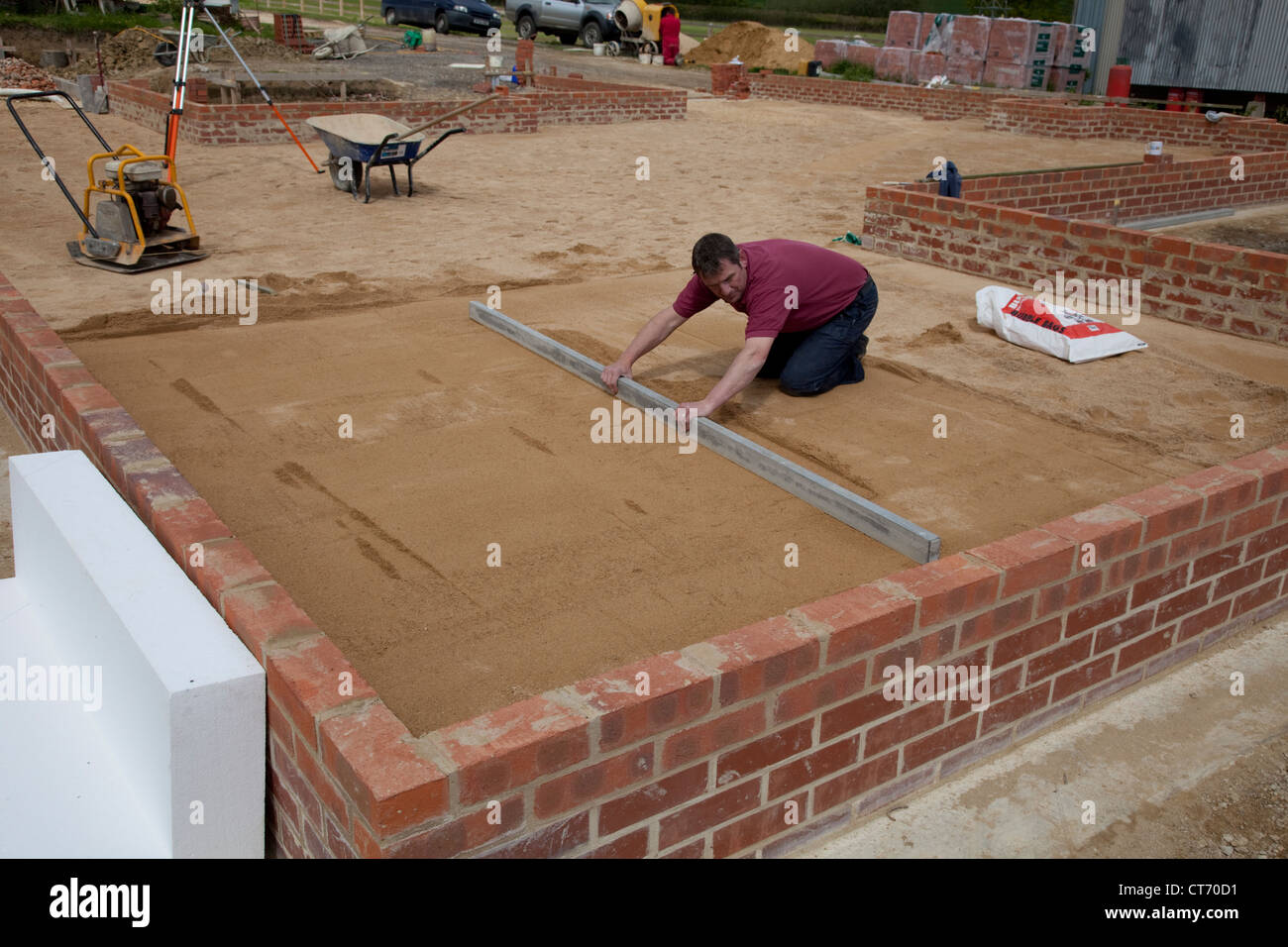 Builder screeding sand layer on passive slab Colemans Hill Farm new build Mickleton Chipping Campden UK Stock Photo