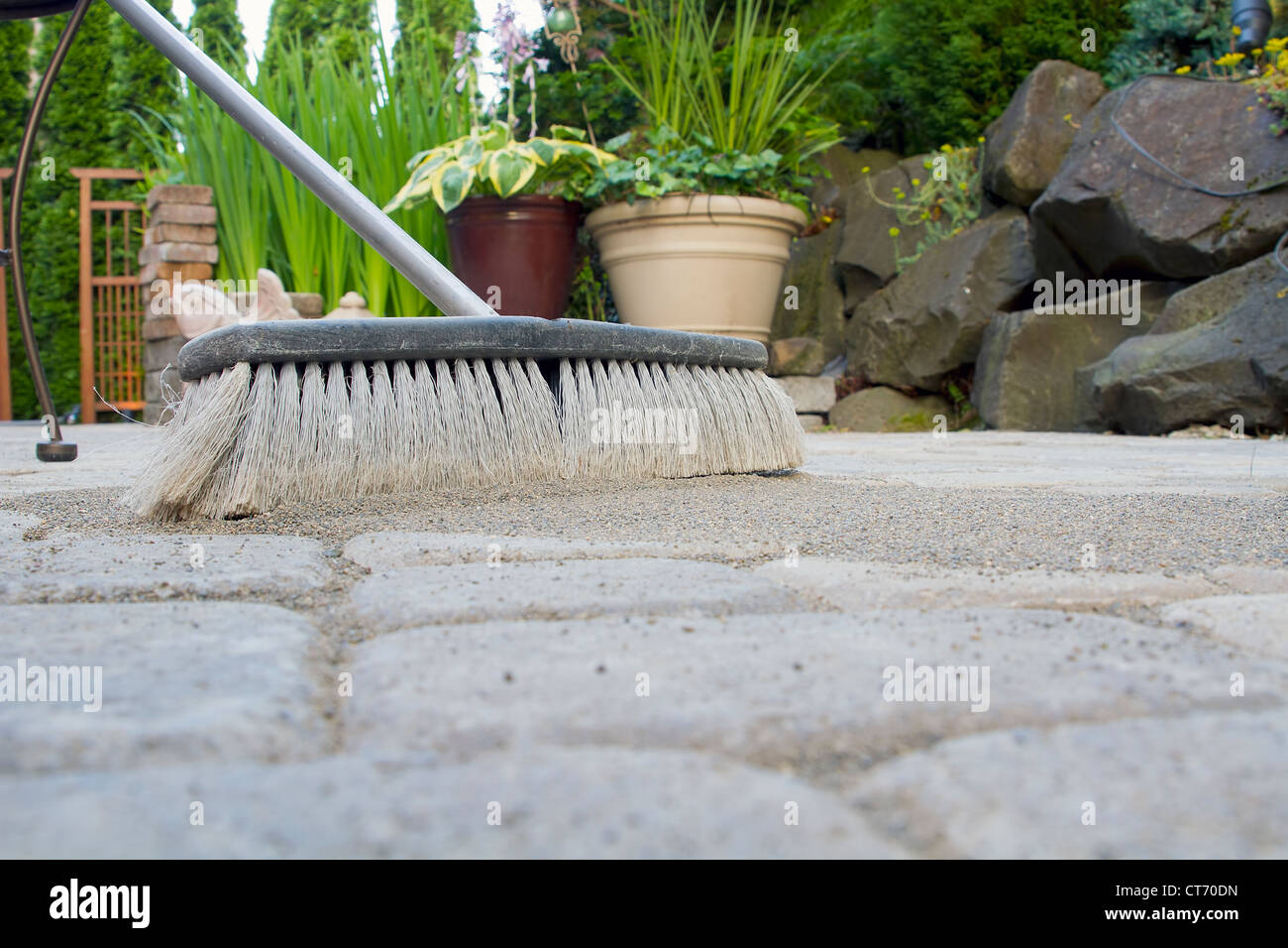Broom Sweeping Locking Sand Into Backyard Patio Pavers Low View Stock