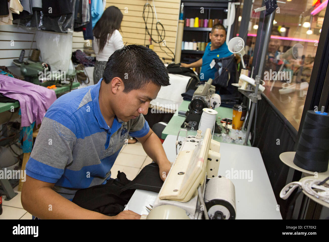 Los Angeles, California - A man sews clothing at a tailor shop in the Los Angeles Fasion District. Stock Photo