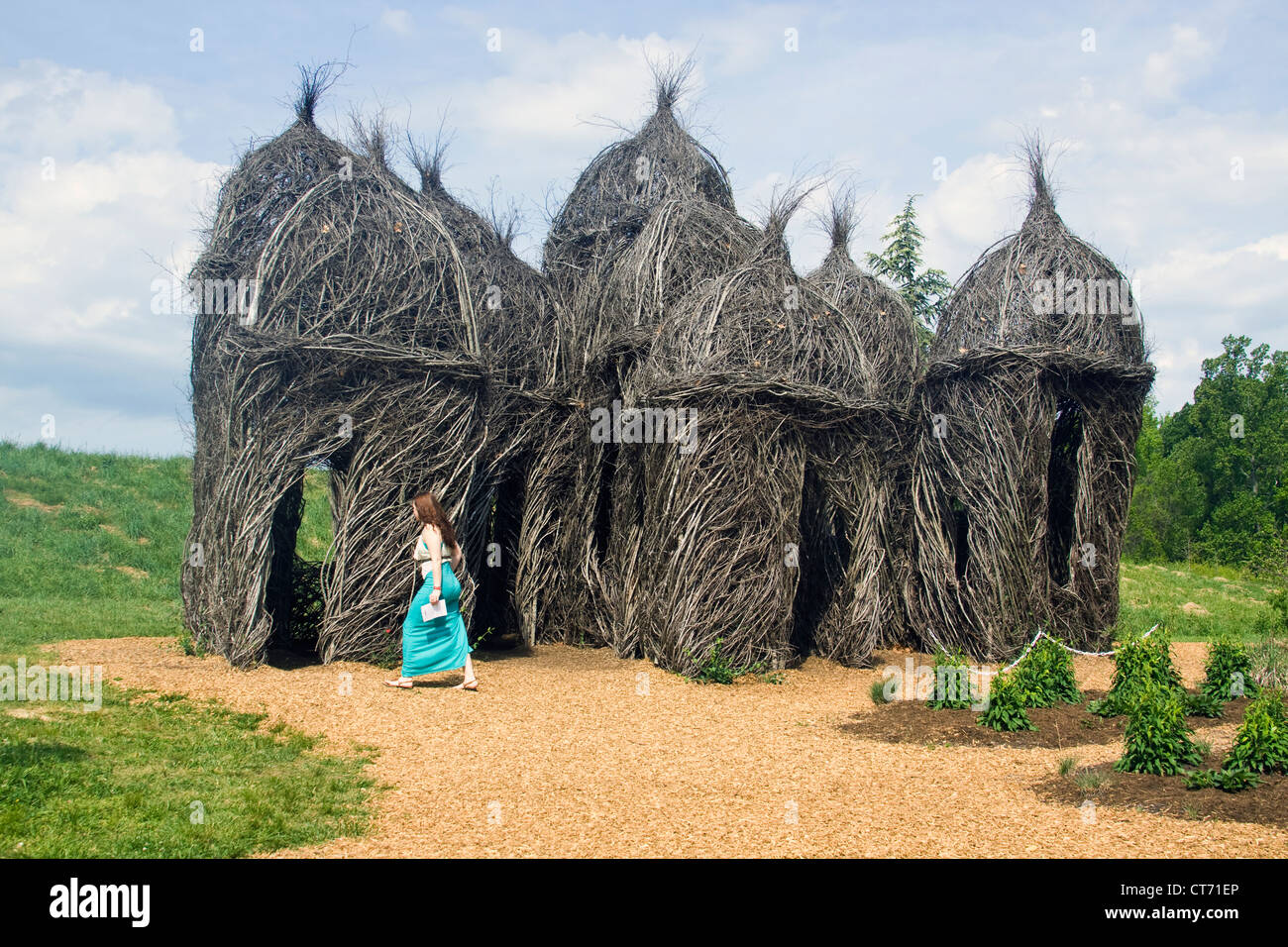 A woman walking to Diamonds in the Rough stick sculpture by Patrick Dougherty at the Lewis Ginter Botanical Garden. Stock Photo