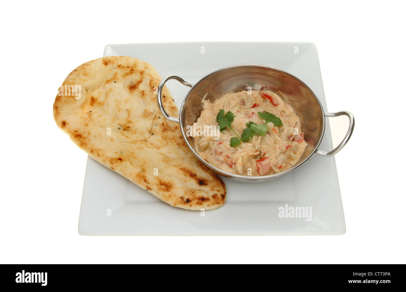 Chicken curry in a balti dish with a naan bread on a plate isolated against white Stock Photo