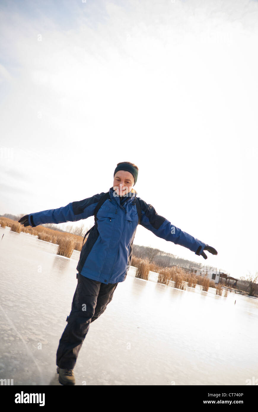 Young smiling woman is sliding on ice winter outdoor scene Stock