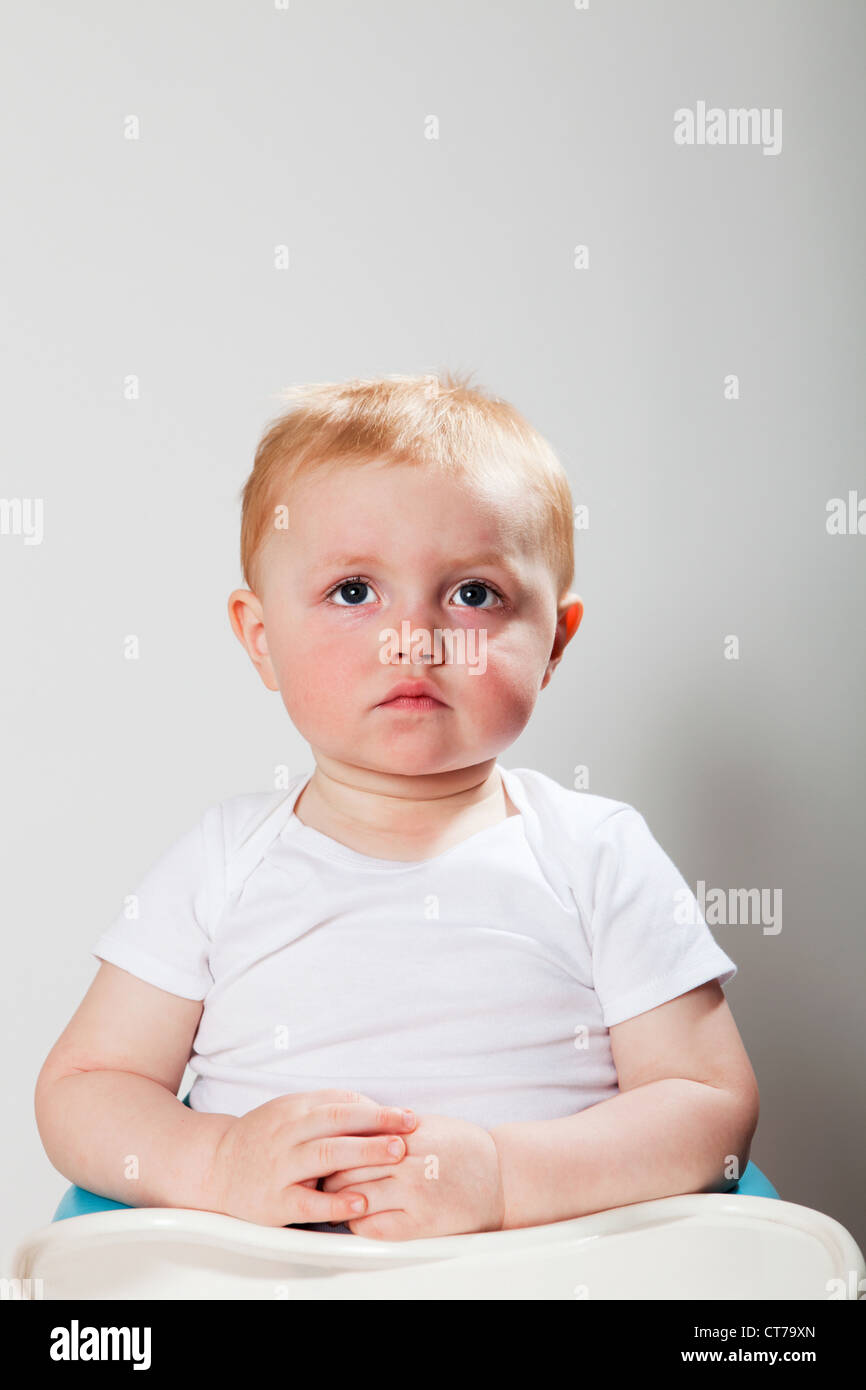 Baby boy sitting in high chair Stock Photo Alamy