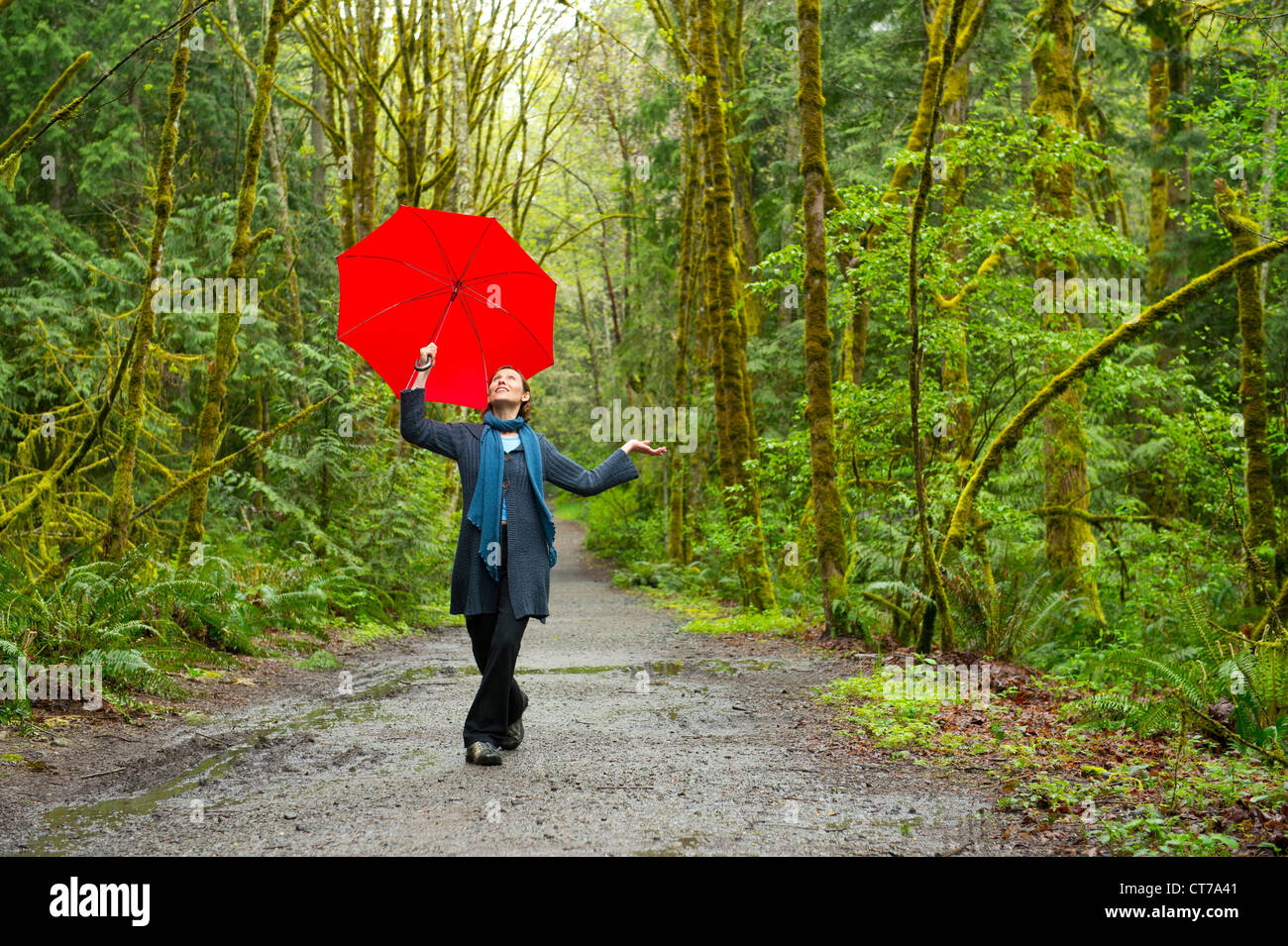 Woman on forest path with red umbrella Stock Photo