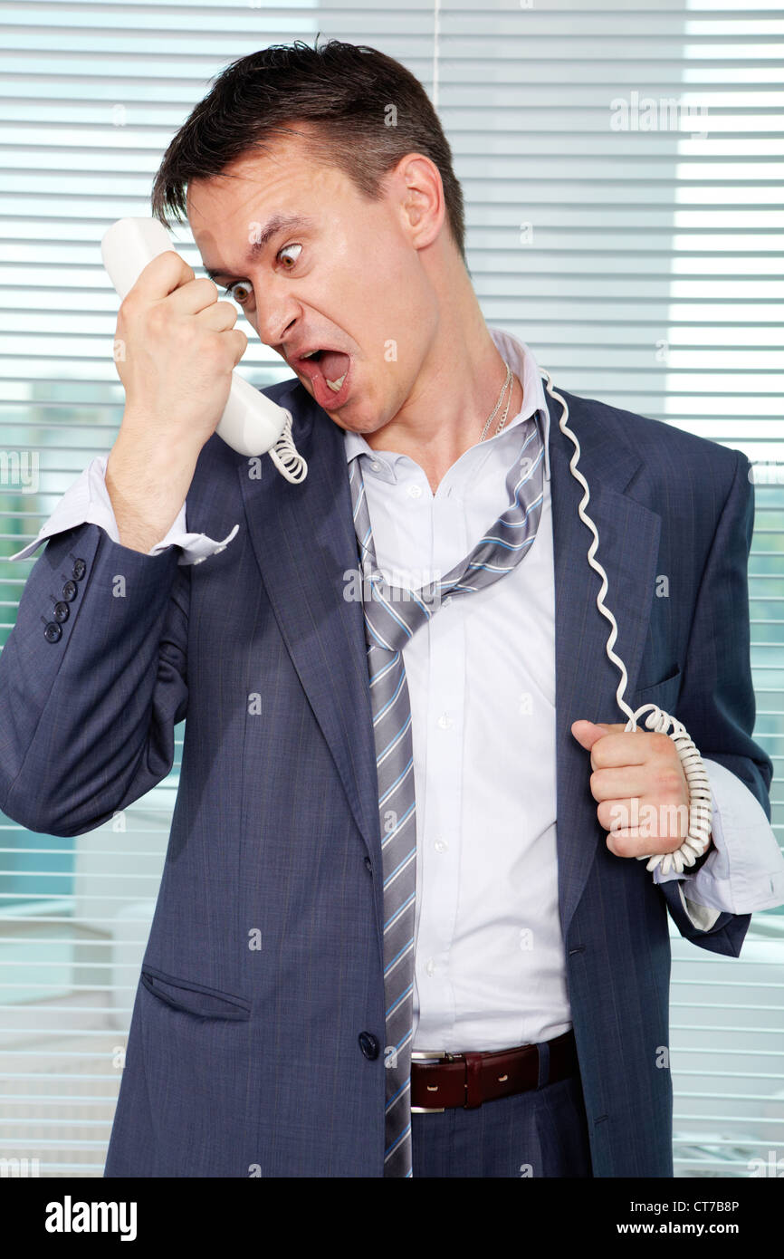Sloppy businessman shouting into phone receiver in office Stock Photo