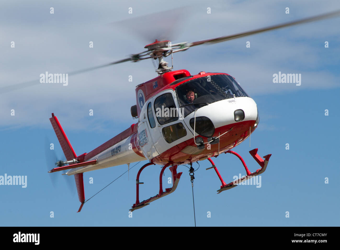 An AS350 Squirrel helicopter hovering with a sling cable attached Stock Photo