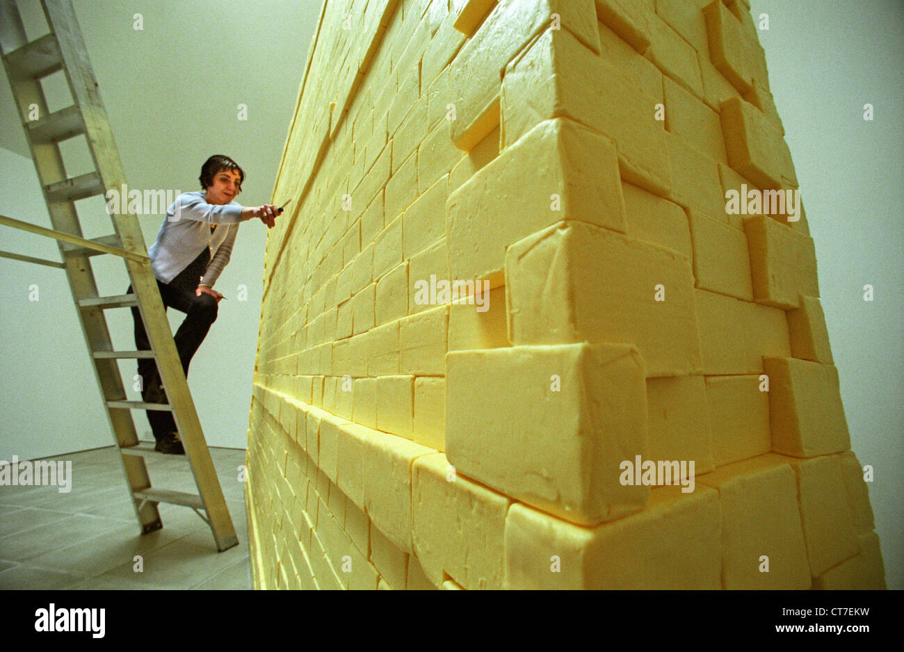 Woman artist on ladder, sculpting a wall made entirely of butter. It weighed three quarters of a ton and was funded with Lottery money. Stock Photo