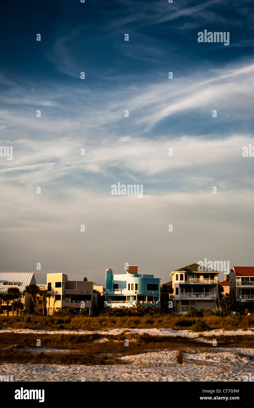 Beach front property sits at the edge of the beach with blue skies and ...
