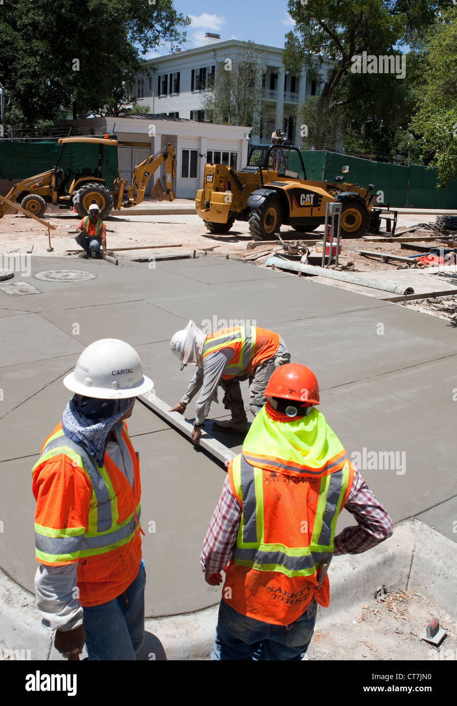 Group of Hispanic male workers complete concrete sidewalk in front of Texas Governor's Mansion in Austin, Texas Stock Photo