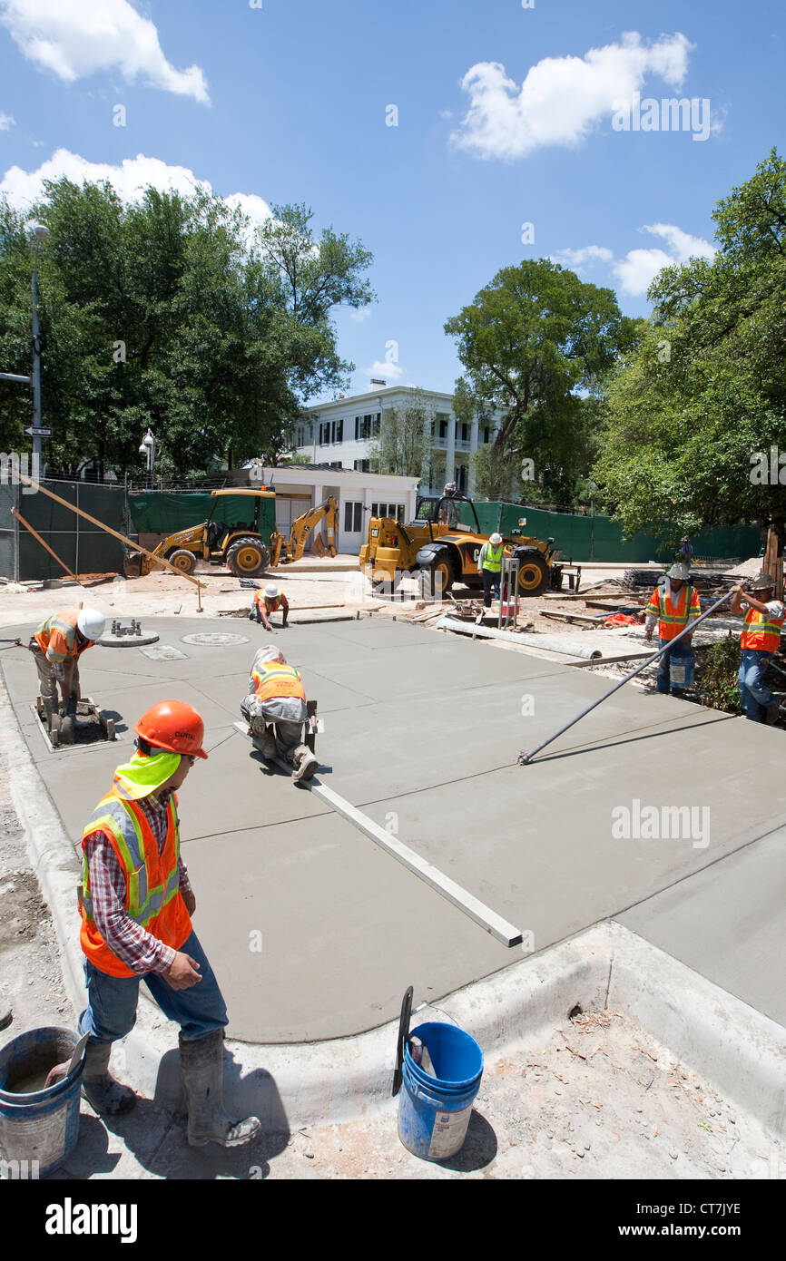 Hispanic male concrete workers complete concrete sidewalk in front of newly renovated Texas Governor's Mansion in Austin, Texas Stock Photo