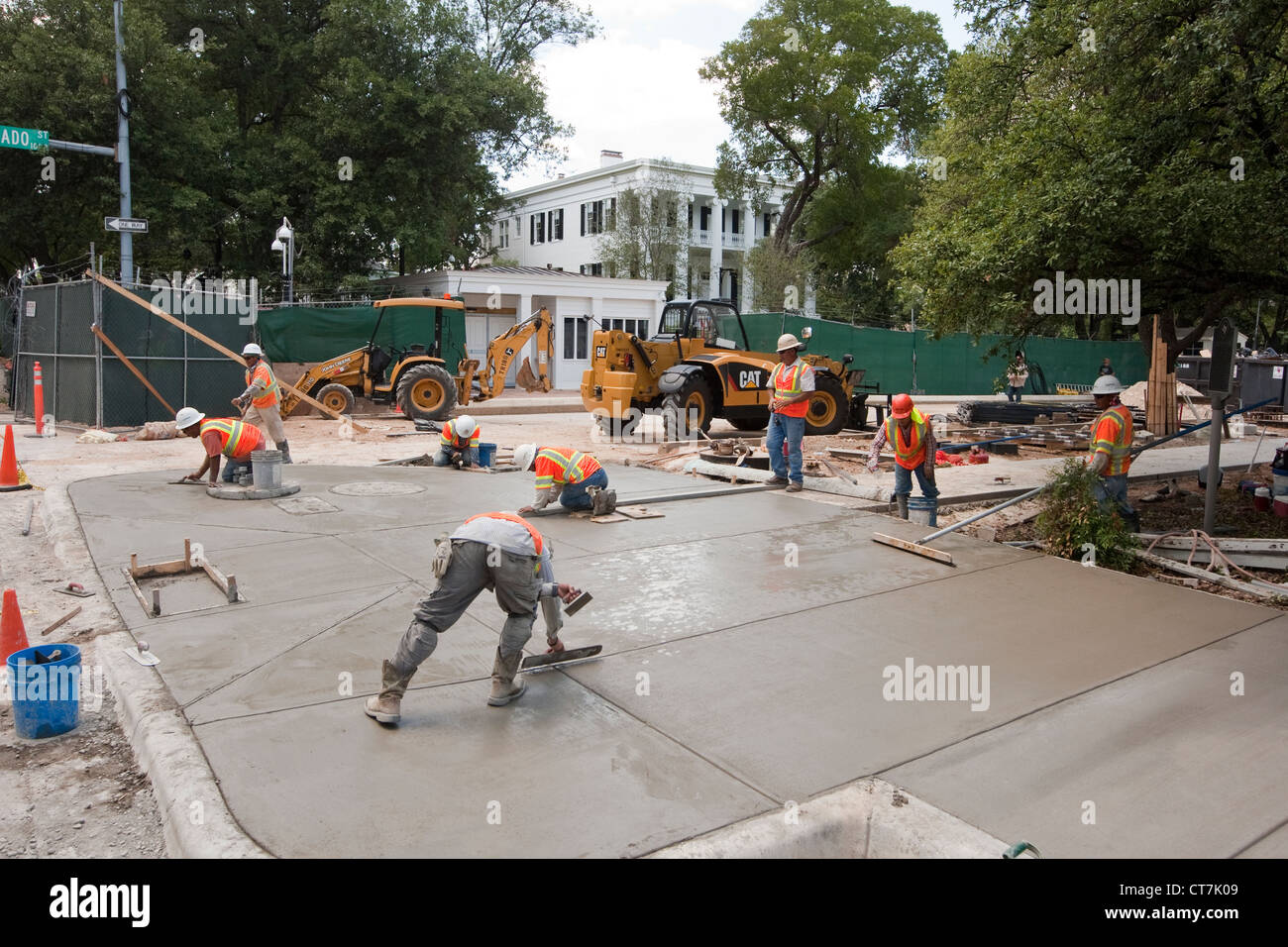 Hispanic male concrete workers complete concrete sidewalk in front of newly renovated Texas Governor's Mansion in Austin, Texas Stock Photo