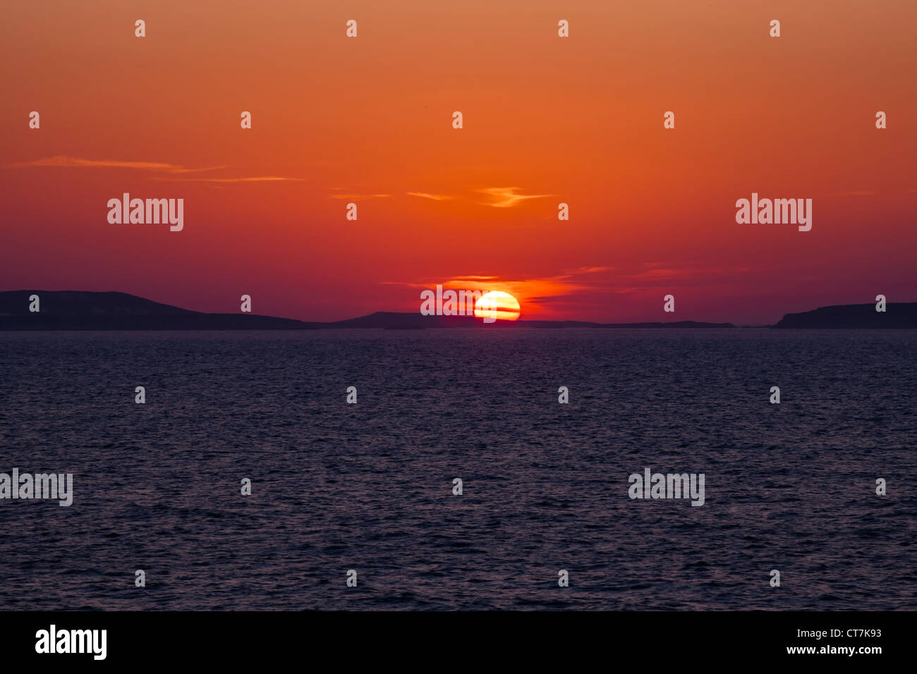 The sun sets behind Paros in the Aegean Sea Stock Photo