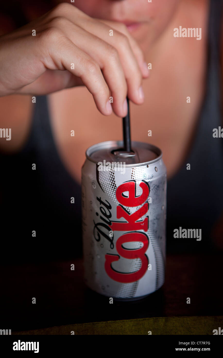 A woman drinks a can of Diet Coke through a straw Stock Photo