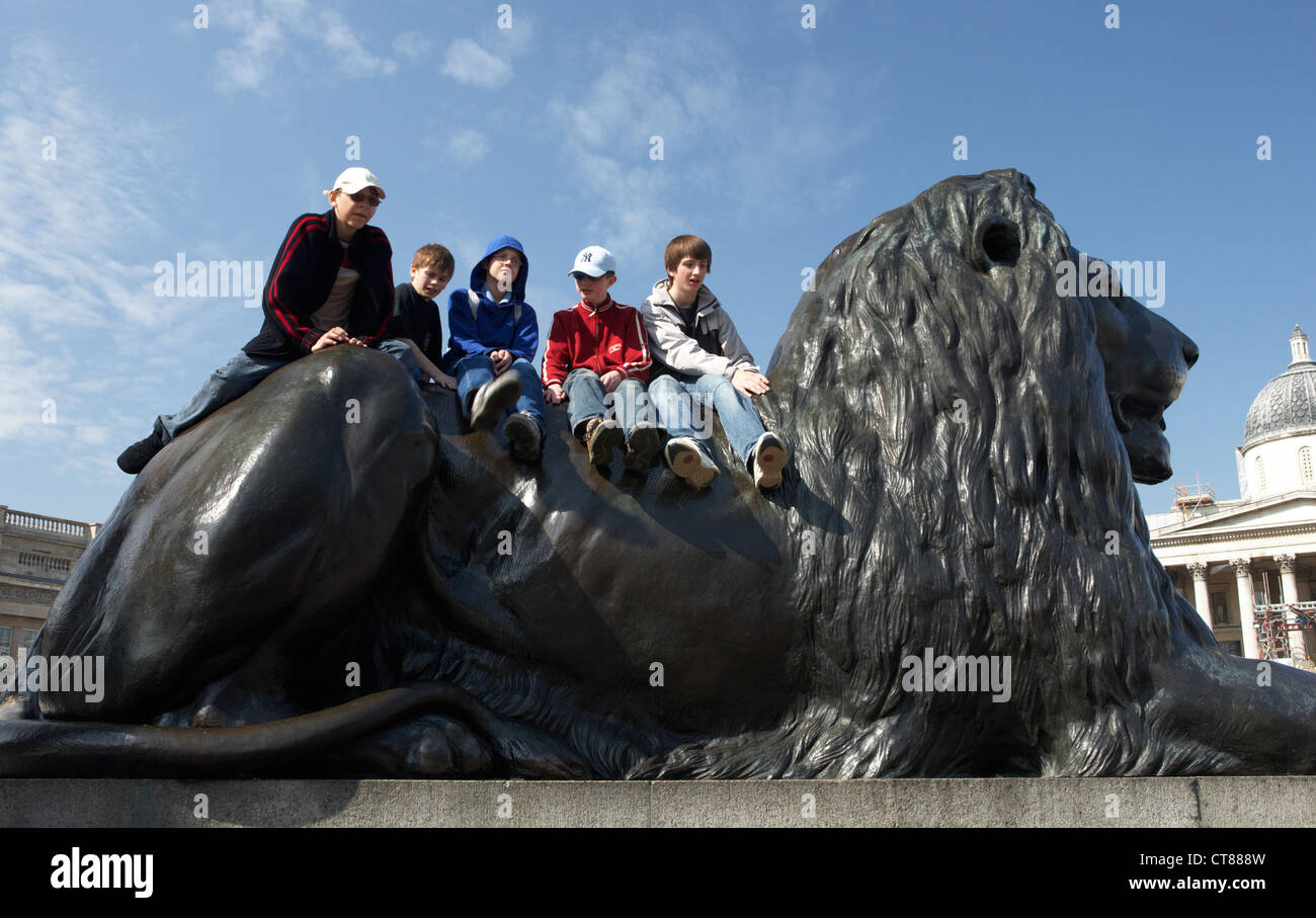 London - boys on a bronze lions in Trafalgar Square Stock Photo