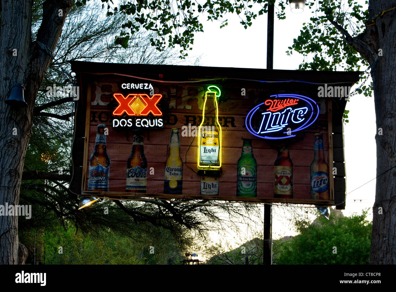 Lit neon beer sign suspended in trees Greasewood Flat outdoor bar dance restaurant Scottsdale AZ Stock Photo