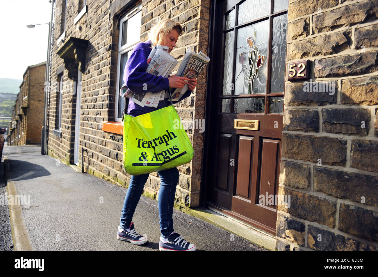 A teenager delivers newspapers to houses on a paper round. MODEL RELEASED Stock Photo