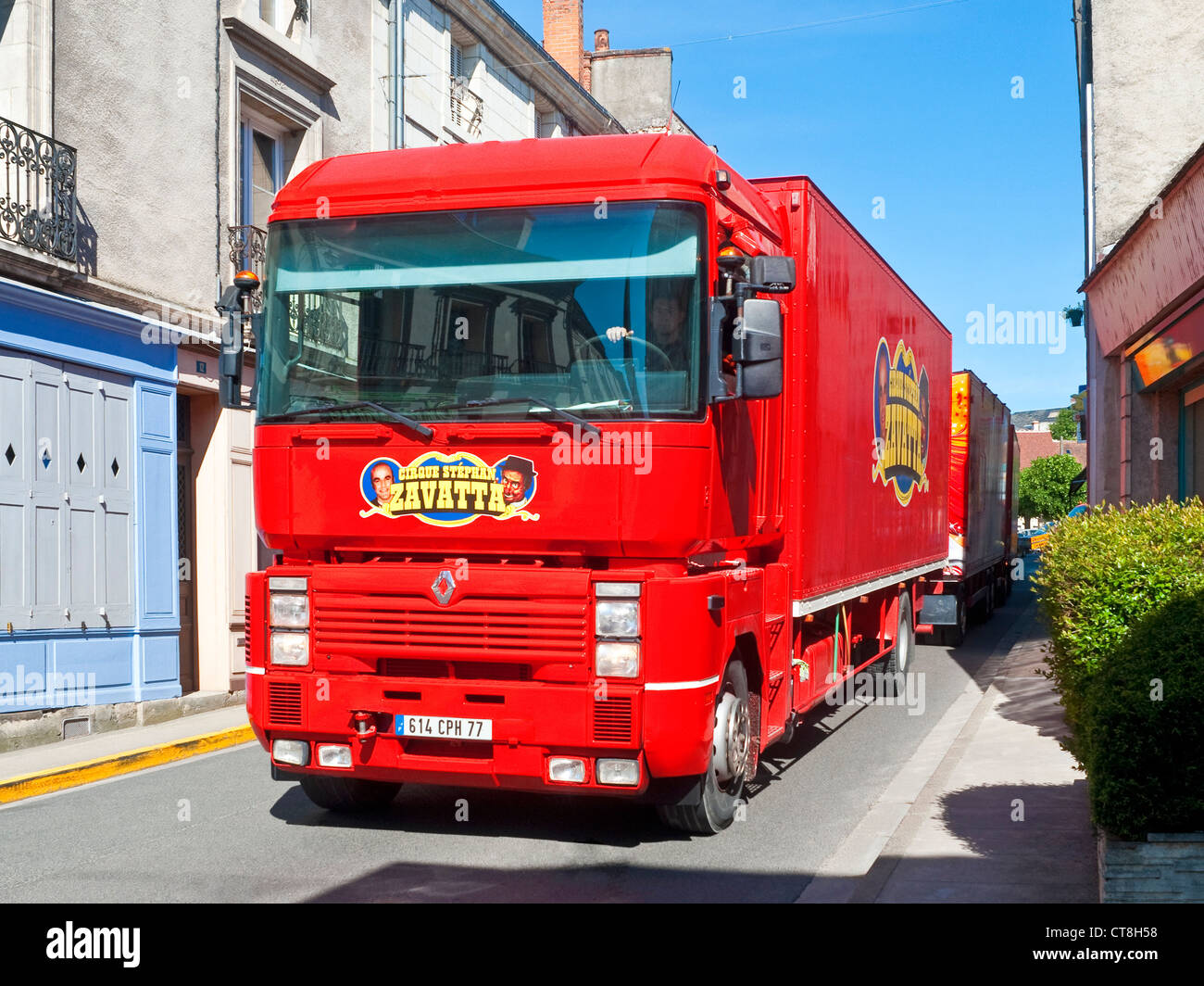 Bright red 'Circus Zavatta' Renault lorry and trailers in narrow town street - France. Stock Photo