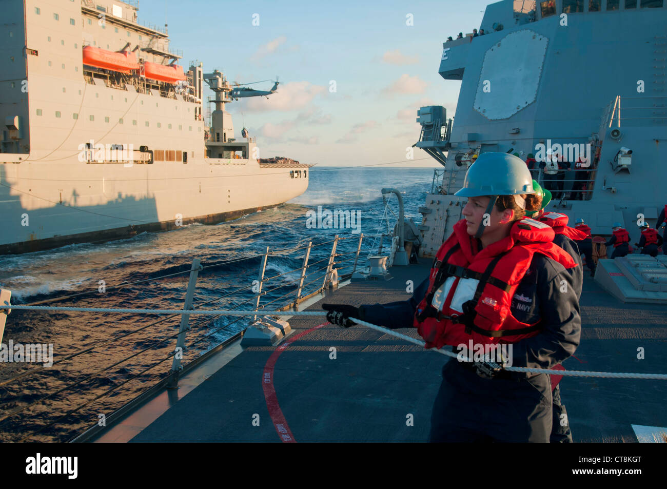 U.S. Navy Fire Controlman 3rd Class Rebccca Griego, assigned to the guided missile destroyer USS McCampbell (DDG 85), heaves in the phone and distance line during a replenishment at sea with the dry cargo and ammunition ship USNS Amelia Earhart (T-AKE 6) in the East China Sea July 8, 2012. McCampbell was under way conducting maritime security operations and theater security cooperation efforts in the U.S. 7th Fleet. Stock Photo