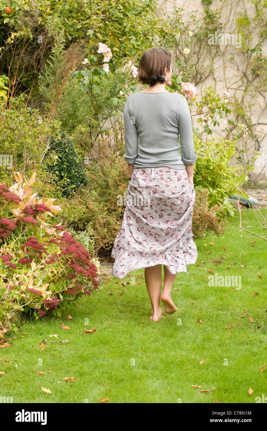 Back view of a teenage girl walking barefoot in her garden Stock Photo