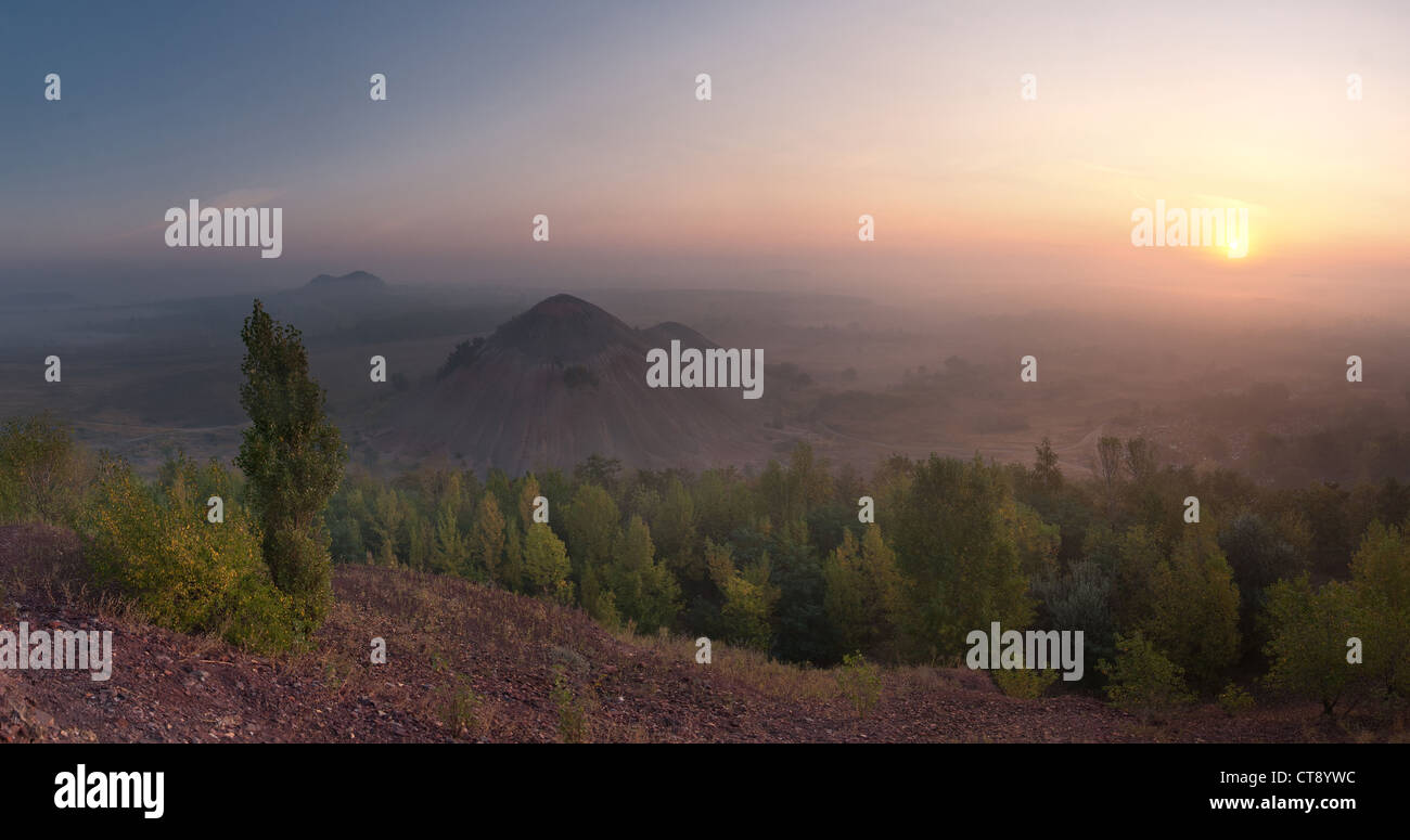 The top view landscape on valley with waste heaps in fog and rising sun Stock Photo