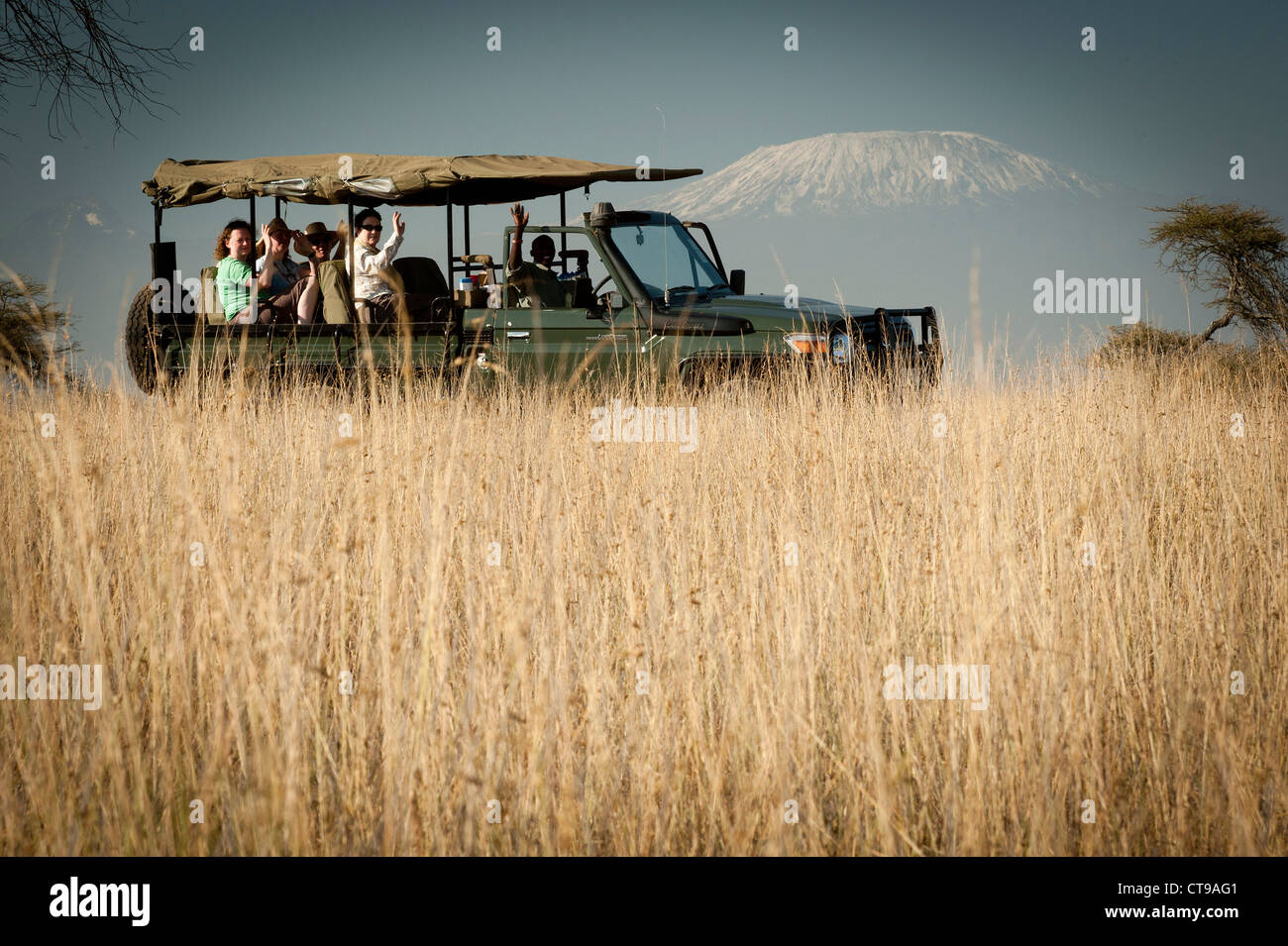 Safari vehicle in long grass with Kilimanjaro beyond Stock Photo