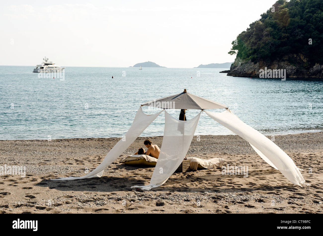Couple relaxing on the beach at l'Eco del Mare hotel part-owned by Italian singer Zucchero Lerici Tuscany Italy Stock Photo
