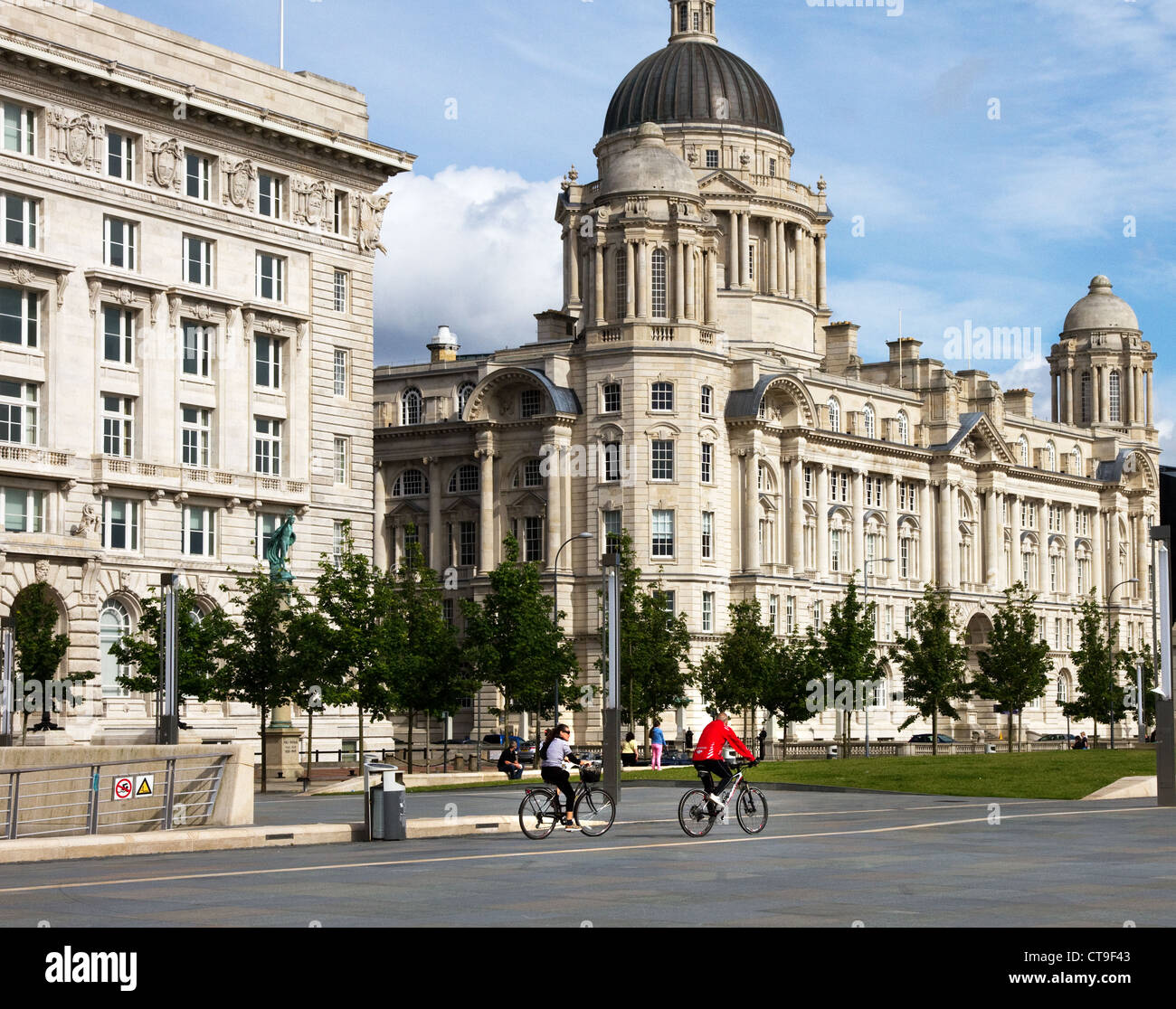 Couple cycling past Cunard Building and Port of Liverpool Building, waterfront, Liverpool, UK Stock Photo