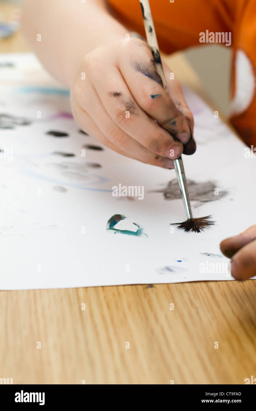 young boy painting a picture with a paintbrush Stock Photo