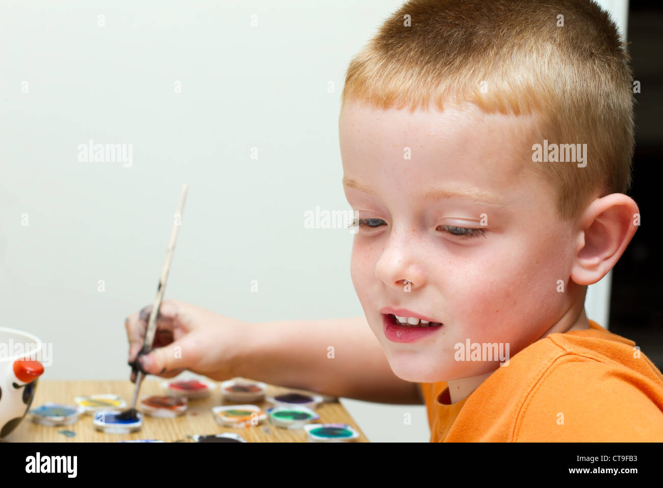 young boy painting a picture with a paintbrush Stock Photo